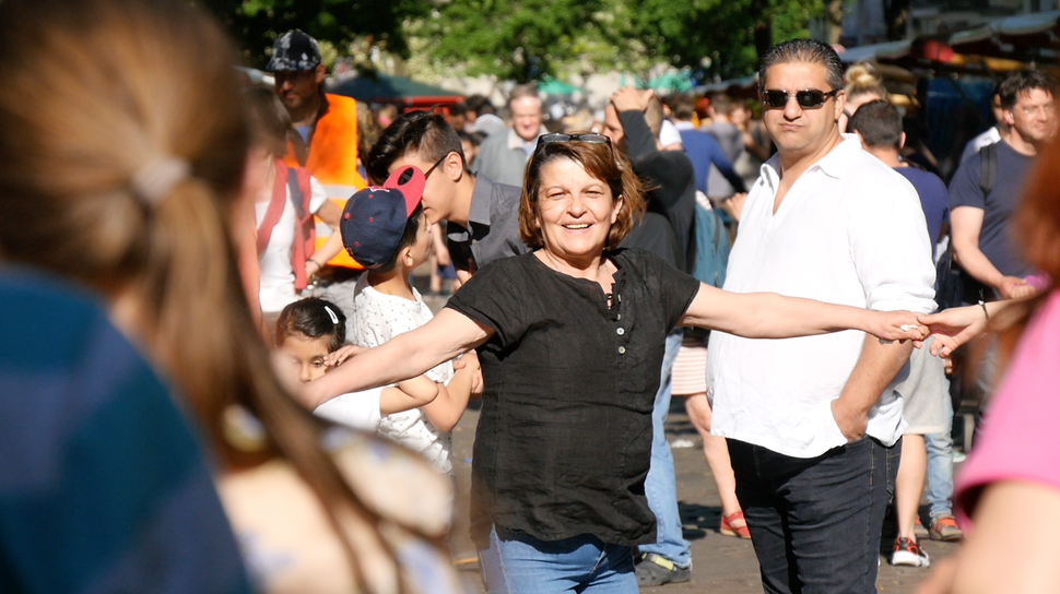 One woman dances in a crowd of Berliners as they listen to traditional Roma music at the 2016 Herdelezi street festival.