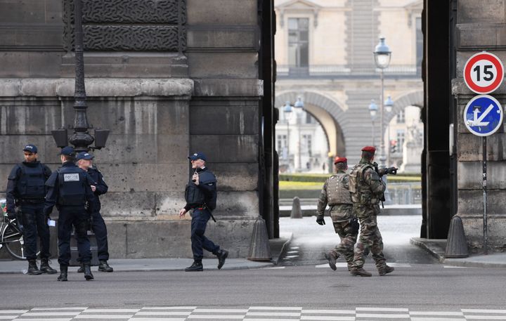 French police officers and soldiers patrol in front of the Louvre museum.