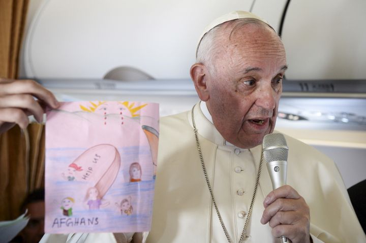 Pope Francis shows drawings made by children on his flight back to Rome following a visit at the Moria refugee camp in the Greek island of Lesbos, April 16, 2016.