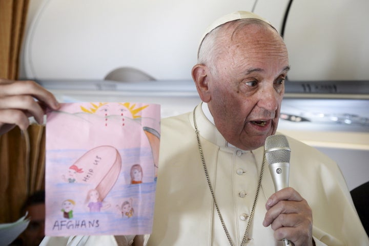 Pope Francis shows drawings made by children on his flight back to Rome following a visit at the Moria refugee camp in the Gr