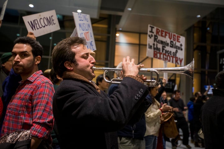 A protester plays "This Land Is Your Land" on a trumpet during a demonstration against the ban on immigration issued by President Donald Trump at Logan International Airport on Jan. 28 in Boston.