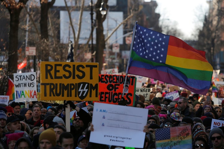 People hold signs during a gathering of the LGBTQ community and supporters protesting against U.S. president Donald Trump's a