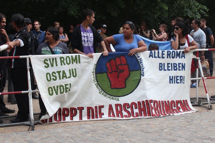 Roma migrants in Germany carry a sign that reads