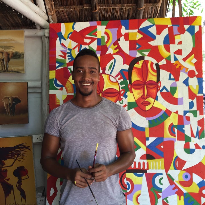 Artist Kevin Peters poses with a cubist painting he created in Diani Beach, Kenya.