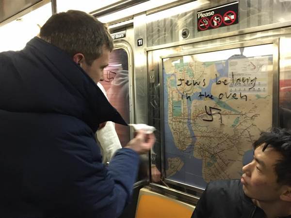 <p>Passenger on Manhattan subway removes anti-Semitic graffiti.</p>