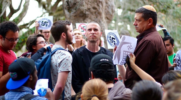 Students and faculty at the University of Florida hold signs reading “Never Again” in protest after Michael Dewitz, center, arrived on campus Jan. 25 wearing a swastika armband.