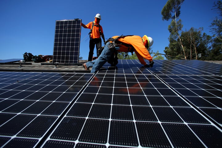 Solar installers from Baker Electric place solar panels on the roof of a residential home in Scripps Ranch, San Diego.