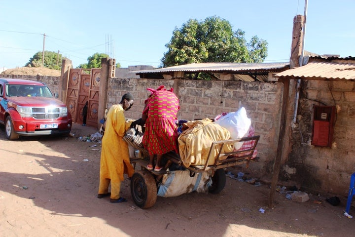 A Gambian man helps his mother onto a donkey cart as they leave a Senegalese border town and head back to their home in Gambia.