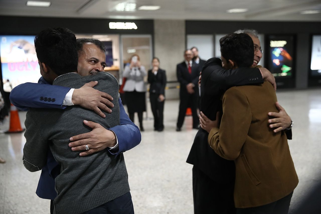Tareq Aquel Mohammed Aziz, left, hugs his father Aquel, second left, as his brother Ammar. second right, hugs his uncle Jamil Assa, right, after the brothers arrived from Yemen at Dulles International airport on February 6, 2017 in Washington, DC.
