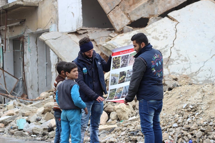Children review manuals distributed by UNICEF-supported volunteers on the risks of unexploded remnants of war, and how to identify and report them, while sitting amid rubble in the Al- Sakhoor neighbourhood of East Aleppo.