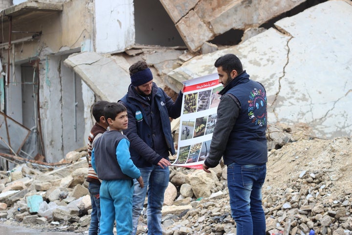 Children review manuals distributed by UNICEF-supported volunteers on the risks of unexploded remnants of war, and how to identify and report them, while sitting amid rubble in the Al- Sakhoor neighbourhood of East Aleppo. 