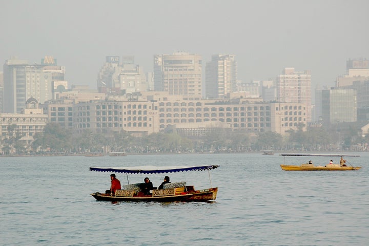 Traditional wooden boats on West Lake against the backdrop of Hangzhou, China’s modern skyline  