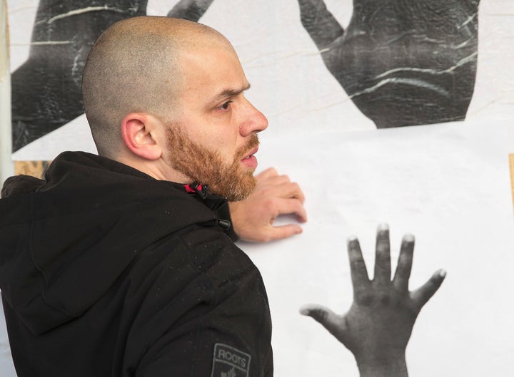 Michael Skolnik helps St. Louis artist Damon Davis (not pictured) install posters from his Push Forward Project on Nov. 19, 2