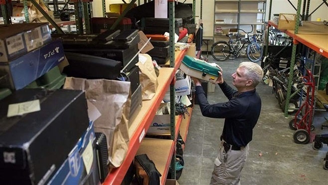 Evidence technician Kit Abernathy of the Vancouver, Washington, Police Department looks over items seized under the civil ass