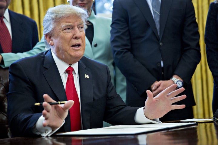 President Donald Trump prepares to sign an executive order that he says will reduce regulations on Jan. 30, 2017. 