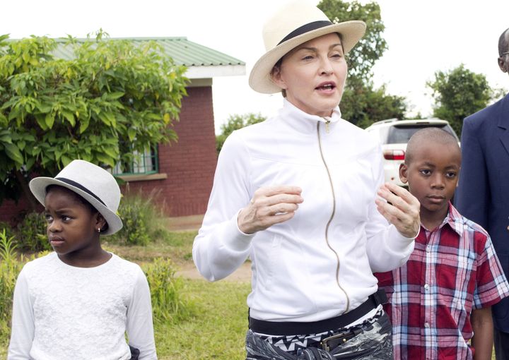 Madonna pictured in 2013 at a tour of the Mphandura orpahange near Lilongwe, Malawi with her two adopted children David Banda and Mercy James.