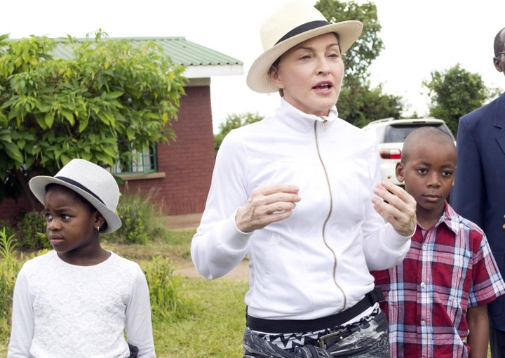 Madonna pictured in 2013 at a tour of the Mphandura orpahange near Lilongwe, Malawi with her two adopted children David Banda and Mercy James.