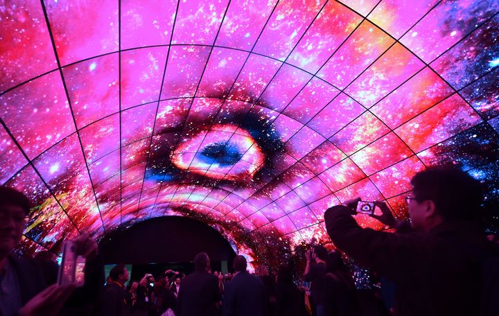 Attendees view a demonstration inside a tunnel ceiling filled with curved and flat 4K OLED TV's from LG at the 2017 Consumer Electronic Show (CES) in Las Vegas.