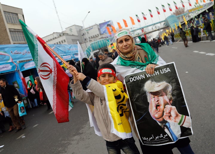 An Iranian woman holds a placard showing a caricature of US President Donald Trump being punched by a hand wearing a bracelet of the Iranian flag during the rally.