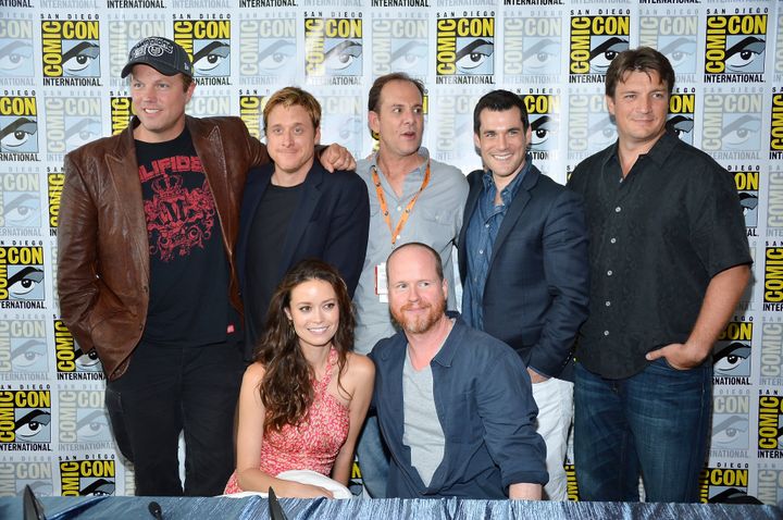 The Cast of Firefly (Standing L–R) Adam Baldwin, Alan Tudyk Tim Minear. Sean Maher, Nathan Fillion, (Kneeling) Summer Glau and Joss Whedon at the 'Firefly' 10 Year Anniversary Reunion at Comic-Con 2012.