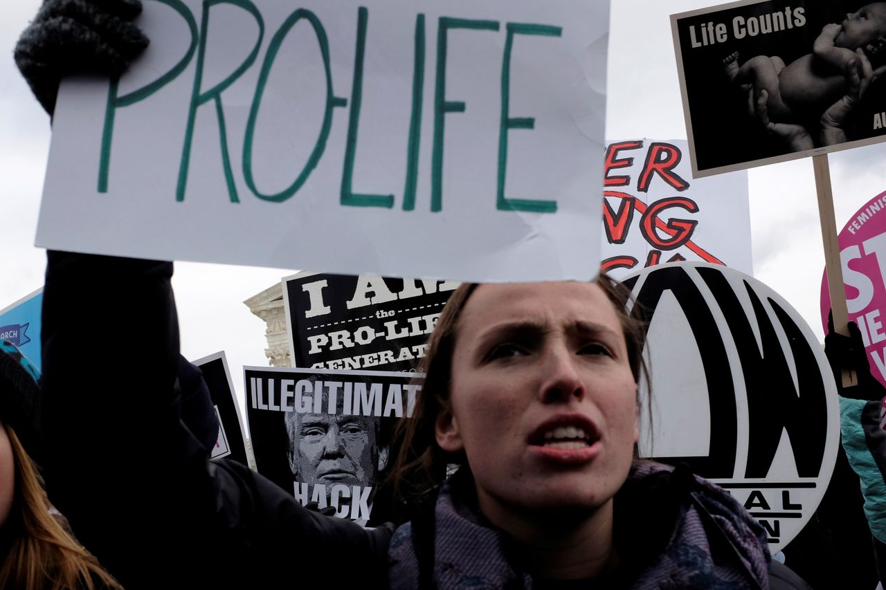 A counter-protester holds an anti-Trump sign behind a pro-life demonstrator as the annual March for Life concludes at the U.S. Supreme Court in Washington, DC, U.S. January 27, 2017.