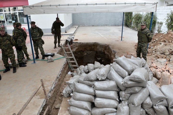 Military personnel of the Hellenic Army Explosive Ordnance Disposal (EOD) team stand at the site of a World War II bomb in Ko