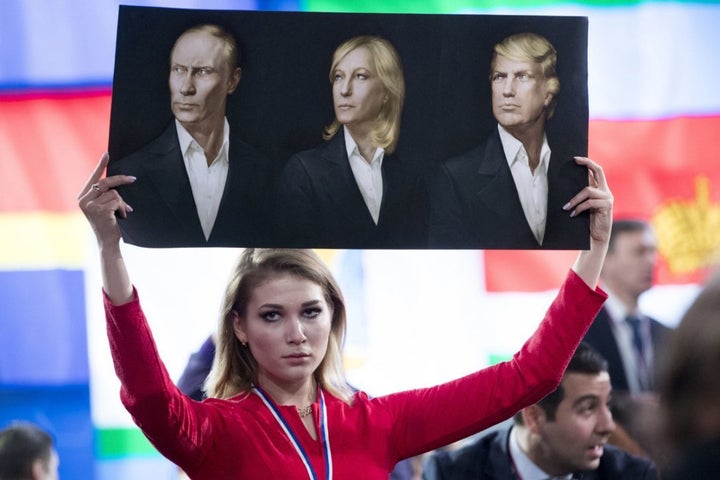 A journalist holds a poster with portraits Vladimir Putin, Marine Le Pen and Donald Trump, prior to Putin's annual news conference in Moscow. 