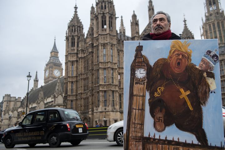 Artist Kaya Mar holds his latest political satire painting of Donald Trump depicted as King Kong with Queen Elizabeth II.