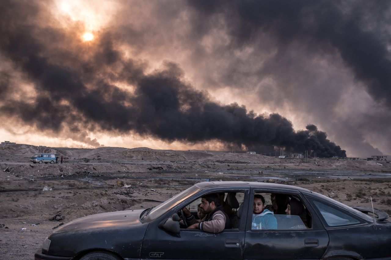 A family flees the fighting in Mosul, Iraq's second-largest city, as oil fields burned in Qayyara, Iraq, on Nov. 12, 2016. This image won second place in the General News stories category.