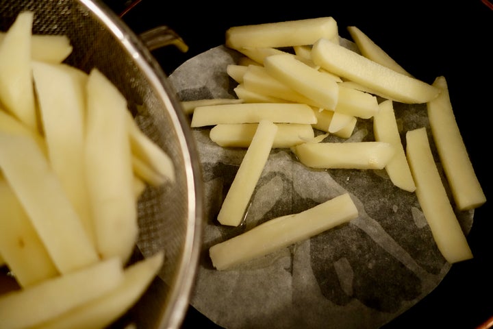 Potatoes and oil are added on top of the parchment paper