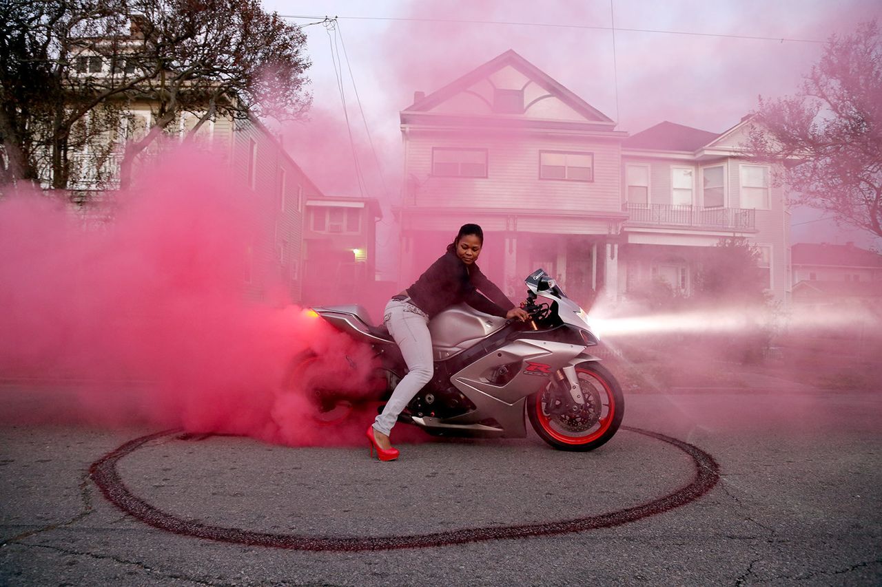 A member of Caramel Curves, an all-women motorcycle group, in a cloud of smoke.