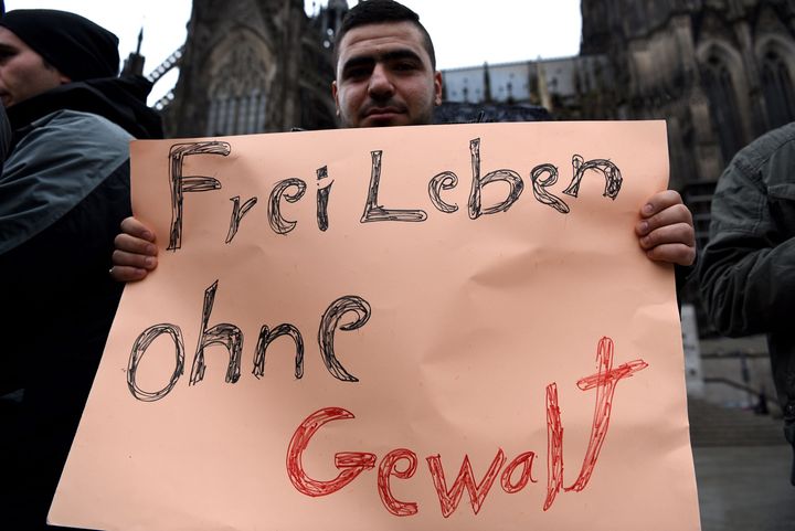 A refugee from Syria holds a sign reading 'Living feely without violence' as they demonstrate against violence at the Cologne main train station, shortly after the New Year's Eve attack there