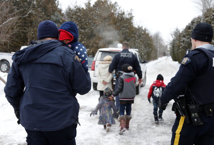 Royal Canadian Mounted Police officers take a Sudanese family into custody after they walked across the U.S.-Canada border into Hemmingford, Quebec, on Feb. 12, 2017.