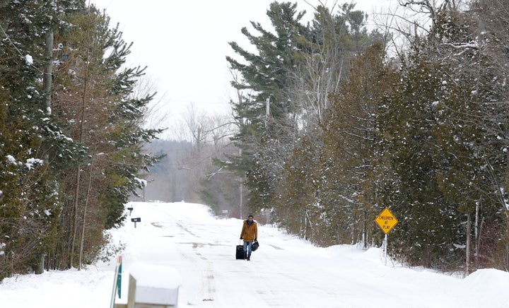 A man walks with his luggage down Roxham Road in Champlain, New York, toward the U.S.-Canada border in Hemmingford, Quebec, on Feb. 13, 2017.