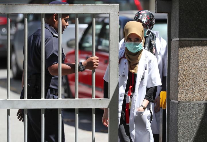 Medical staff exit the gate of the forensic department at the hospital in Kuala Lumpur.