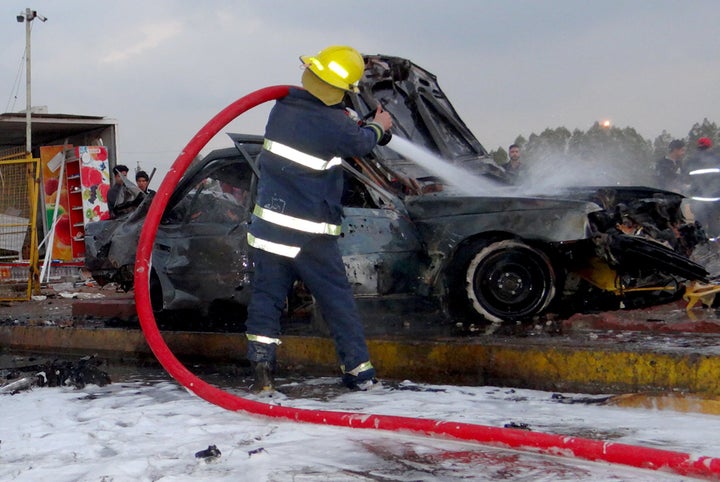 Firefighters try to extinguish fire at the site of a suicide car bomb attack in the eastern Habibiya neighborhood of Baghdad,