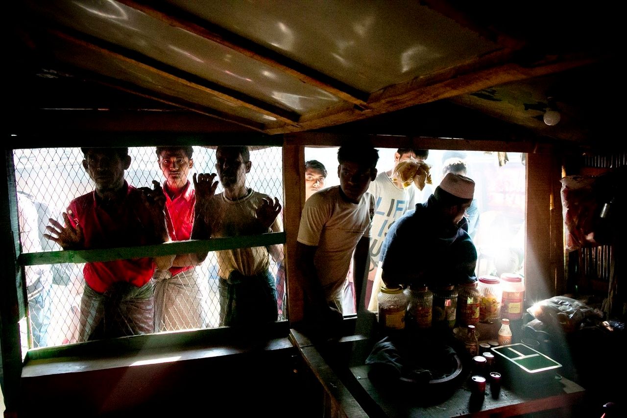 Rohingya refugees peer through the screen of a restaurant in Kutapalong.