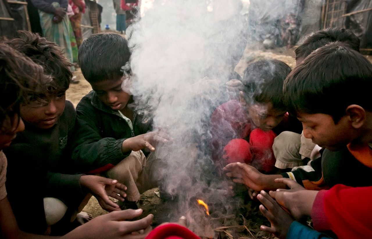 Newly arrived Rohingya children warm themselves by a fire in Kutapalong.