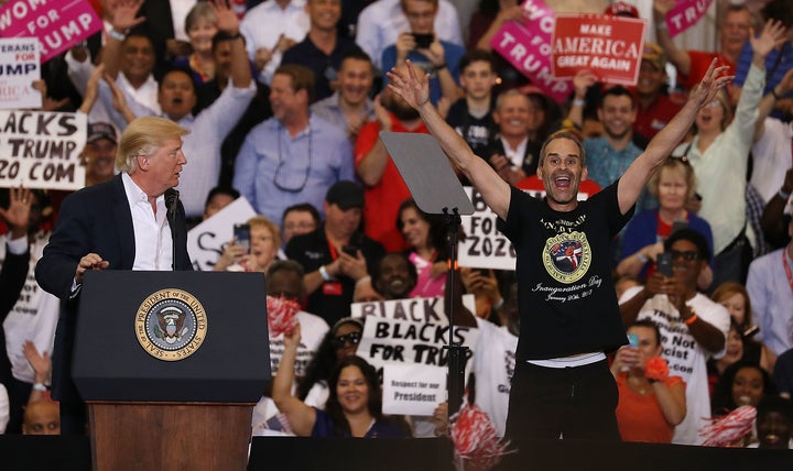 President Donald Trump looks on after asking Gene Huber to speak during a campaign rally at the AeroMod International hangar
