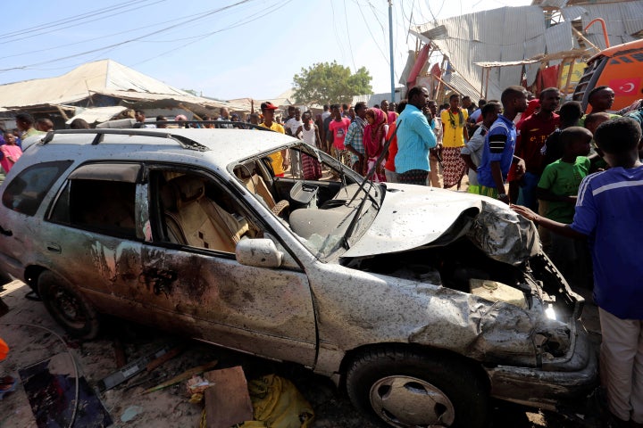 Civilians stand near a car destroyed in a suicide bomb explosion at the Wadajir market in Madina district of Somalia's capital Mogadishu, February 19, 2017. (REUTERS/Feisal Omar)