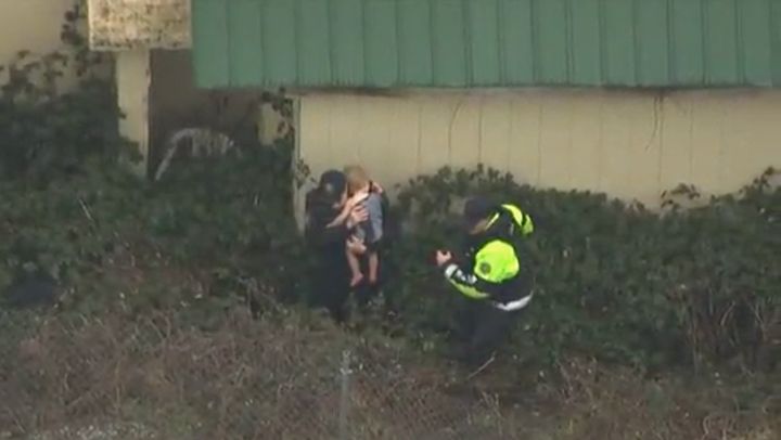 Two officers are seen recovering a 2-year-old child from some bushes after the child went missing from his Portland, Oregon home Saturday.
