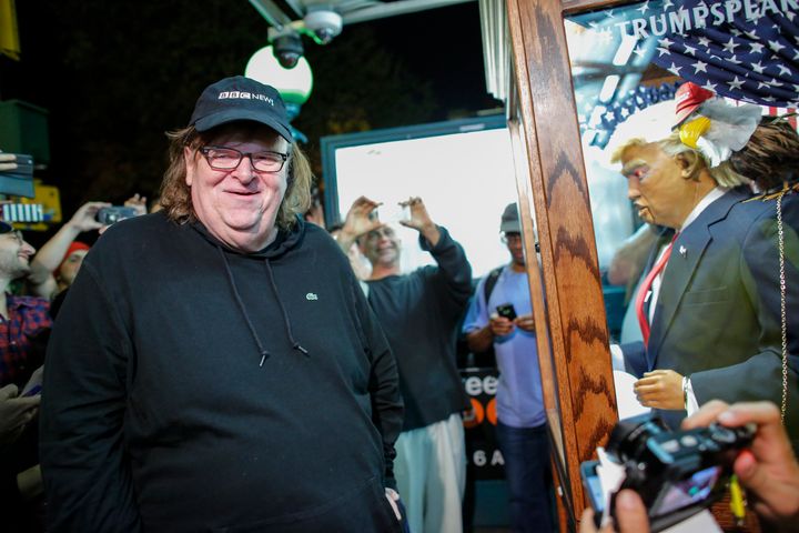 Michael Moore smiles as he listen to a fortune-telling attraction bearing the likeness of Donald Trump, before attending the debut of the 'TrumpLand' documentary -- New York on October 18, 2016.