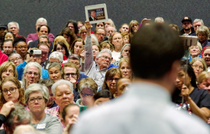 Unhappy constituents hold up signs during Rep. Scott Taylor's town hall meeting at Kempsville High School in Virginia Be