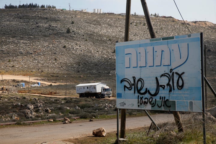 A sign covered in text reading, "we will return, I swear," marks the road leading to an illegal Israeli outpost of Amona, in the occupied West Bank on Feb. 6, 2017.