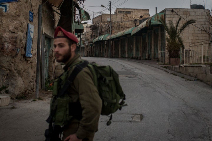 An Israeli soldier stands guard at a checkpoint on a street that separates an Israeli settlement and a Palestinian neighborhood inside the city of Hebron on Jan. 18, 2017 in Hebron, West Bank.