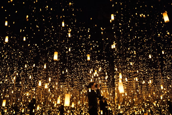 A woman photographs inside the "Aftermath of Obliteration of Eternity" infinity room.