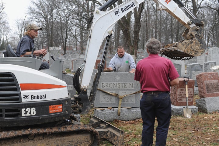 Volunteers from a local monument company help to reset vandalized headstones at Chesed Shel Emeth Cemetery on Wednesday in University City, Missouri.