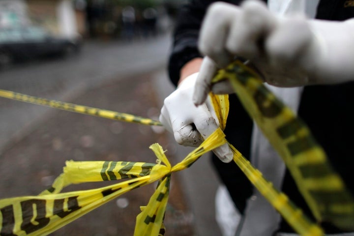 A forensic technician ties a used police line together to seal off a crime scene in Monterrey.