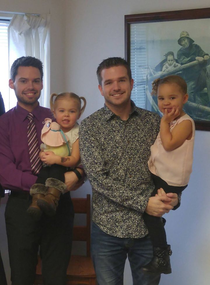 John (left) holds Emery and Nathan holds Brynn at the adoption signing for Emery