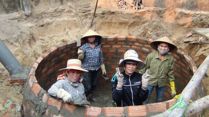 Vietnamese trained female masons construct biogas digesters.
